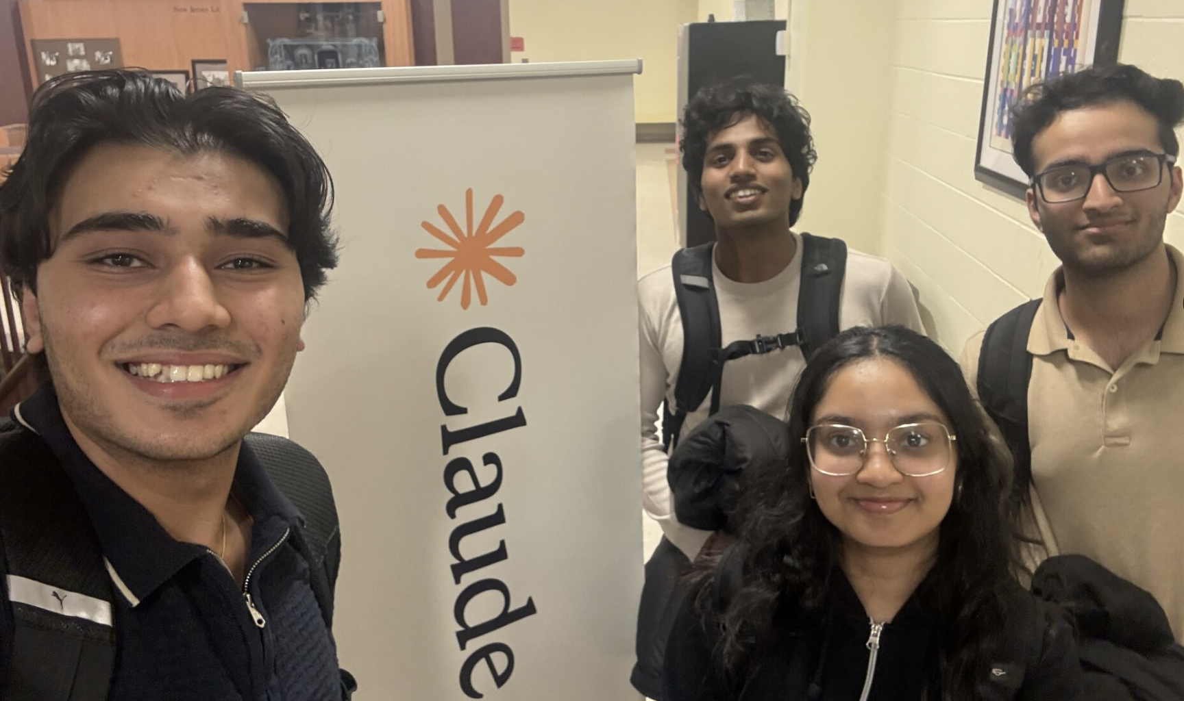 Rishab and his AdaptIQ team beside a Claude banner